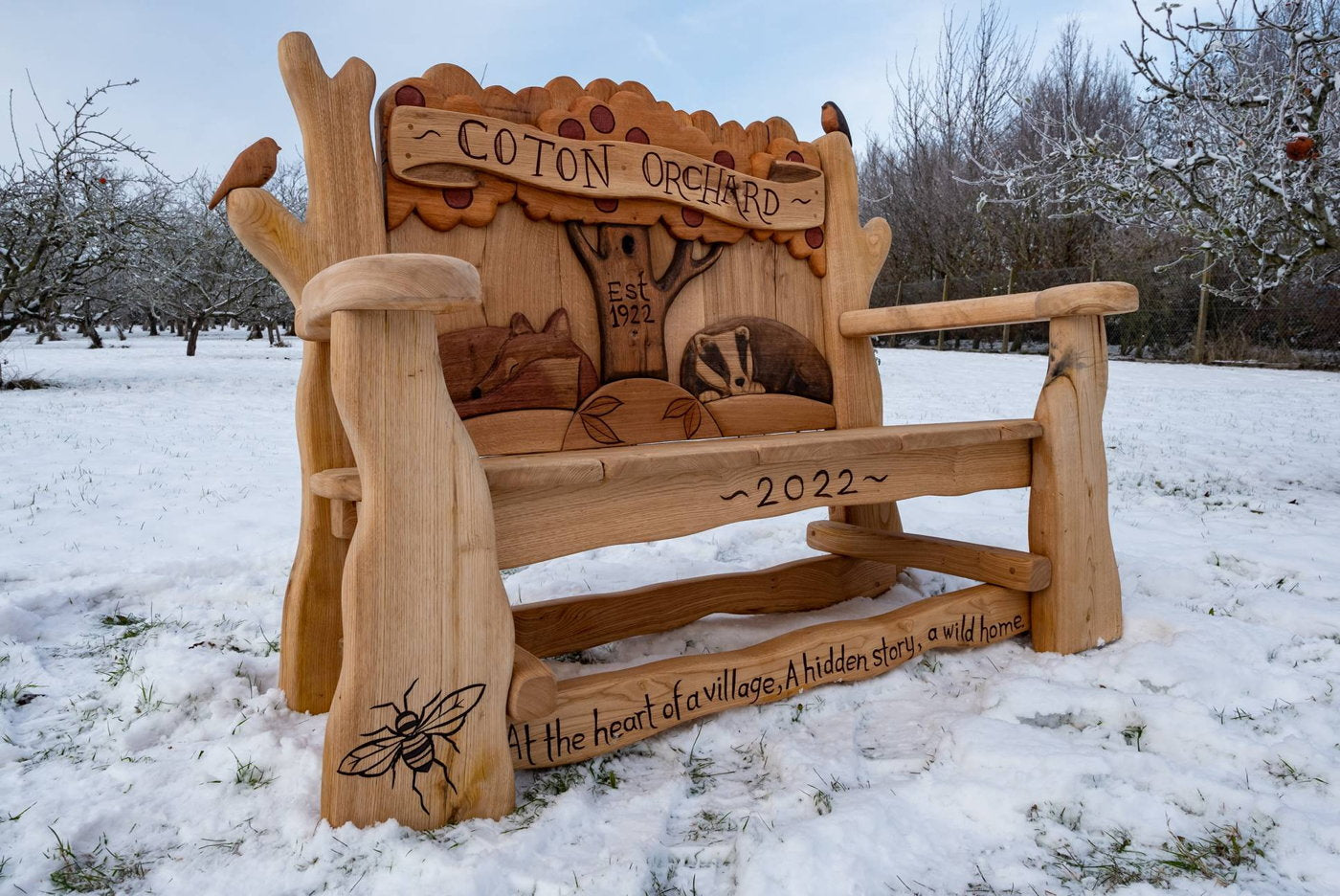 Coton Orchard bench with wildlife carvings and date.