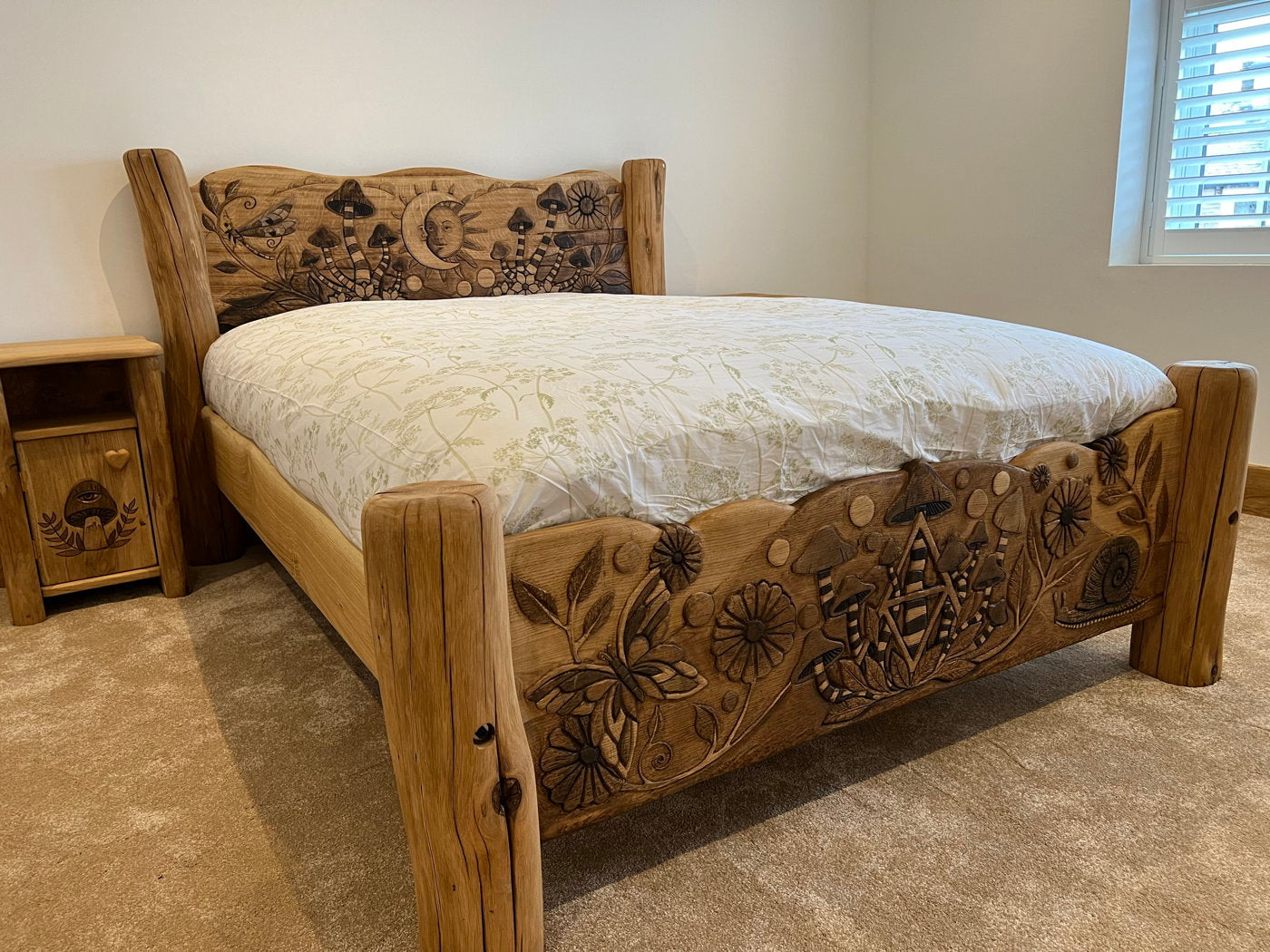 Oak bed with intricate carvings in a bedroom