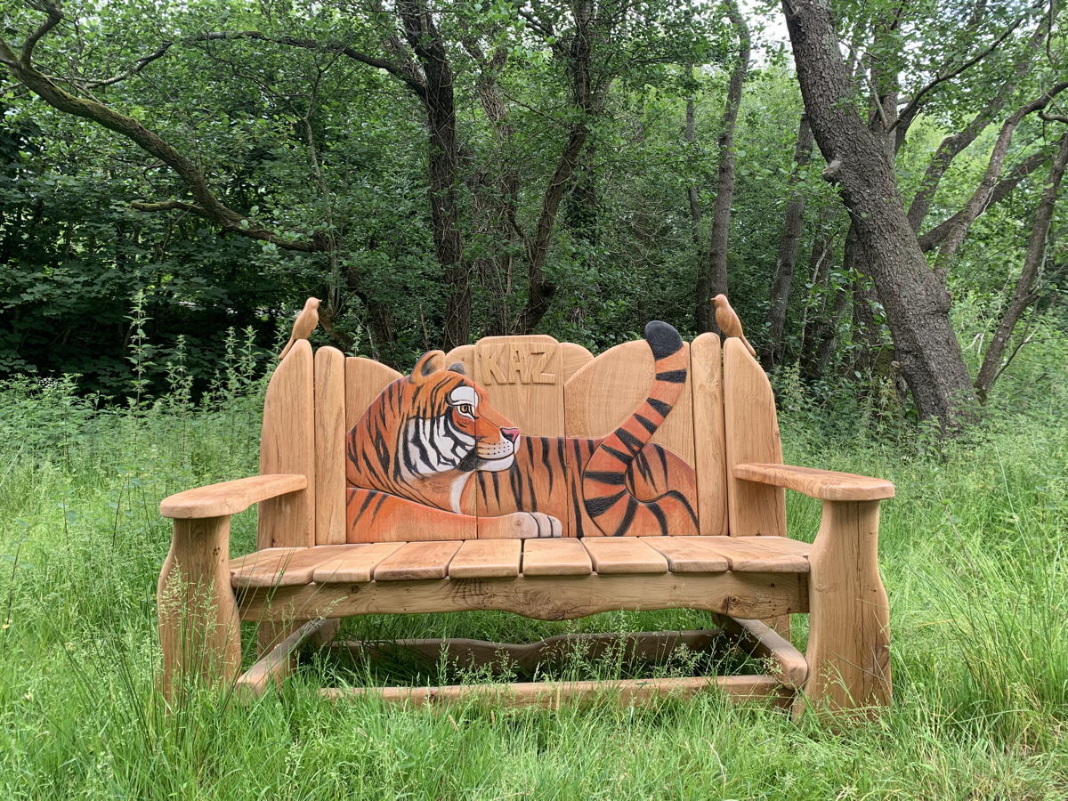 Wooden bench with tiger design surrounded by greenery