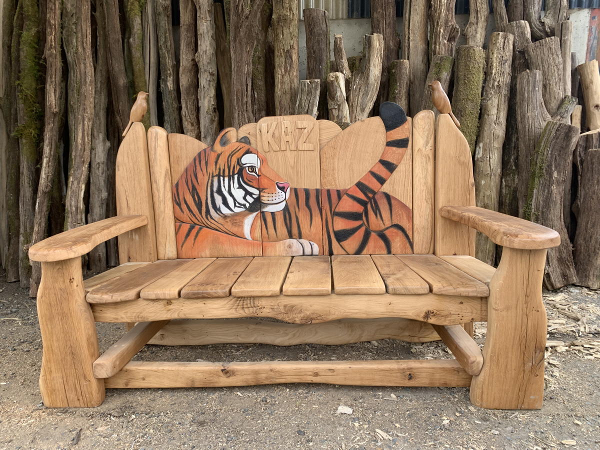 Rustic wooden bench featuring a carved tiger, set against logs