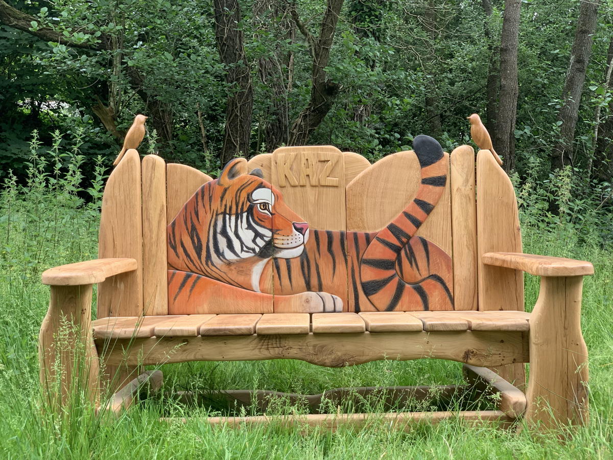 Wooden bench with tiger carving in a grassy area