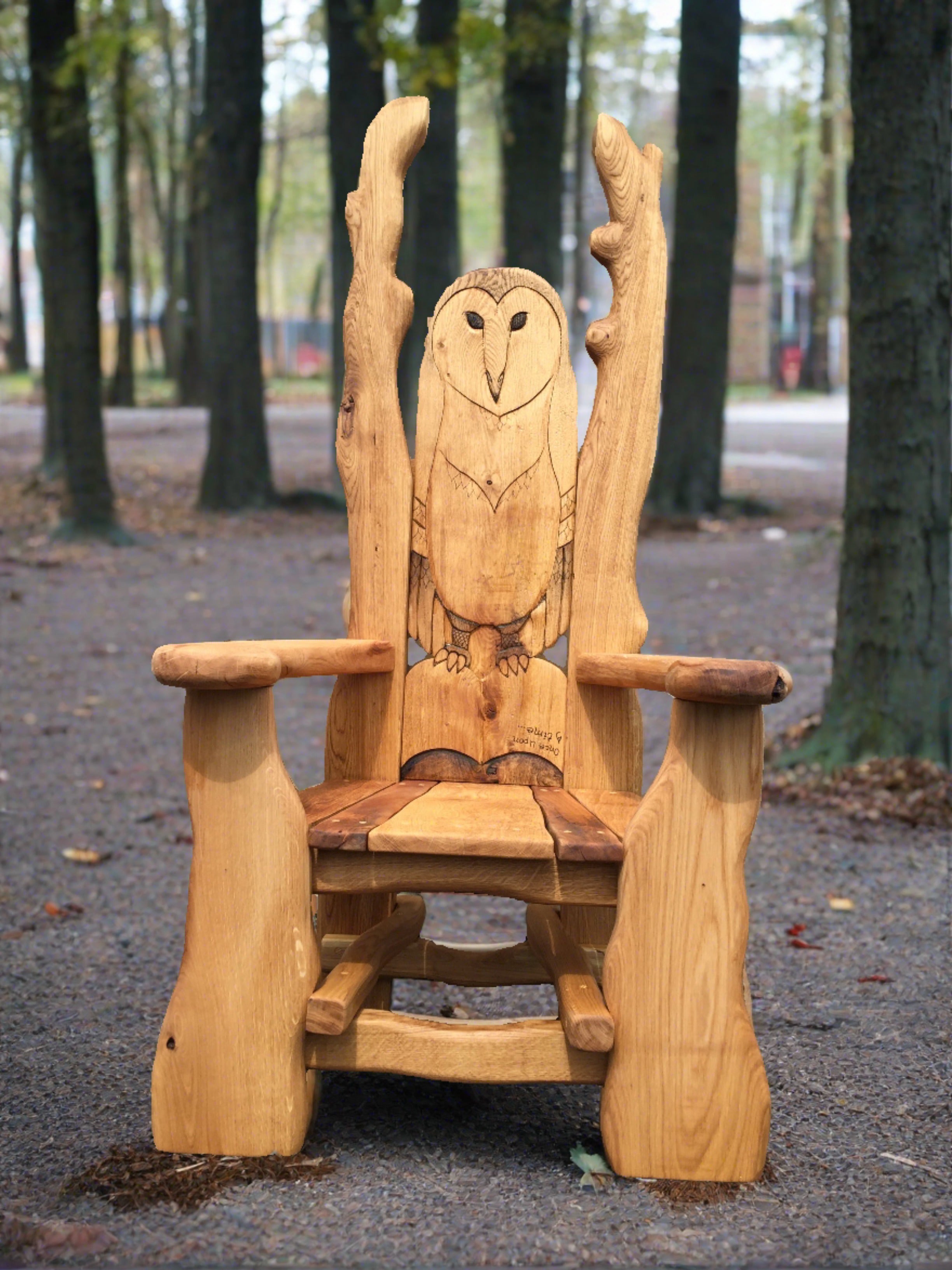 Wooden chair with carved owl in a forest setting.