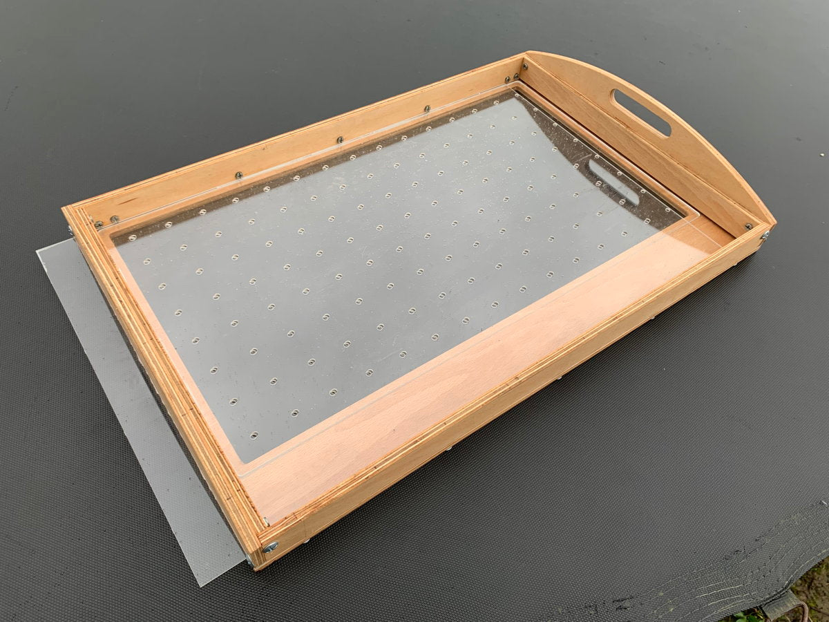 Wooden mechanical seed sowing tray on dark surface