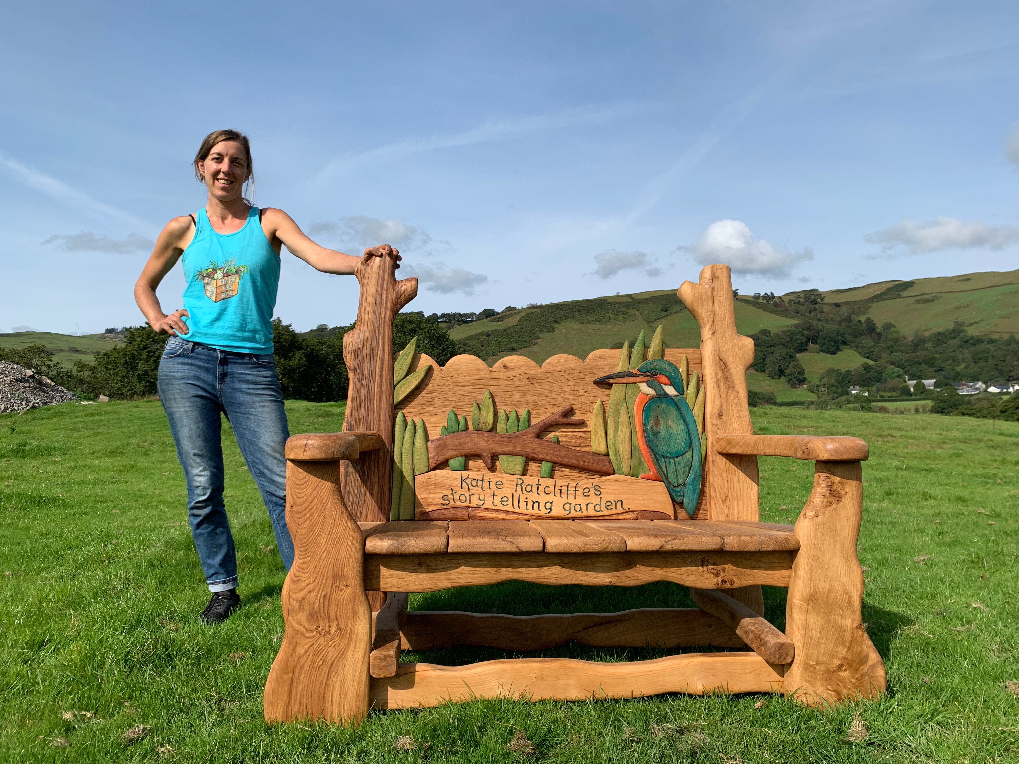 Woman standing beside oak storytelling garden bench